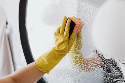 House cleaning services cleaning mirror with sponge