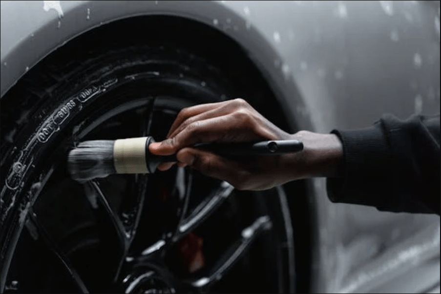 A person cleaning a tire of a car
